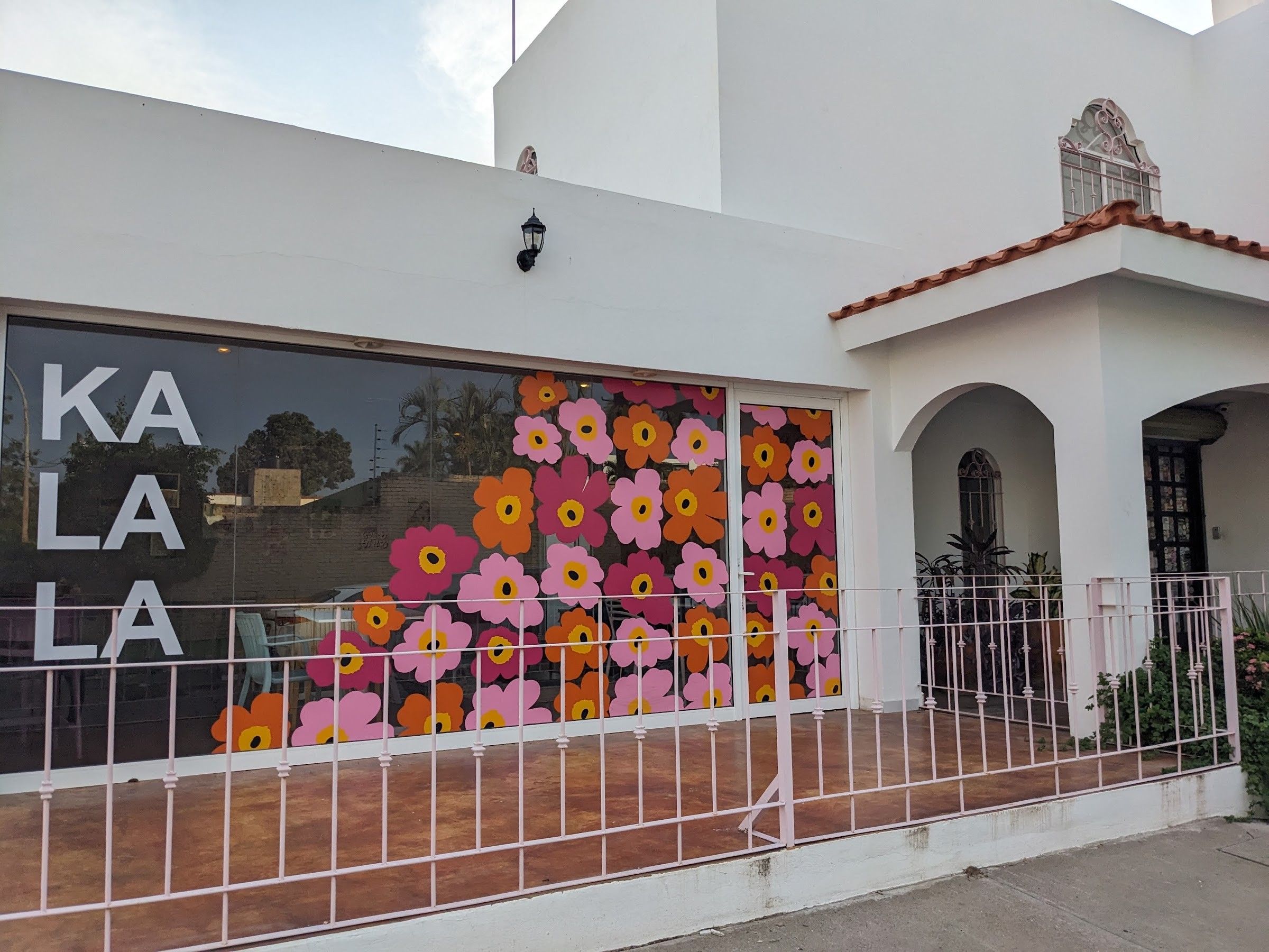 La casa blanca de Kalala en Chapule, con flores pintadas en el ventanal y barandal rosa